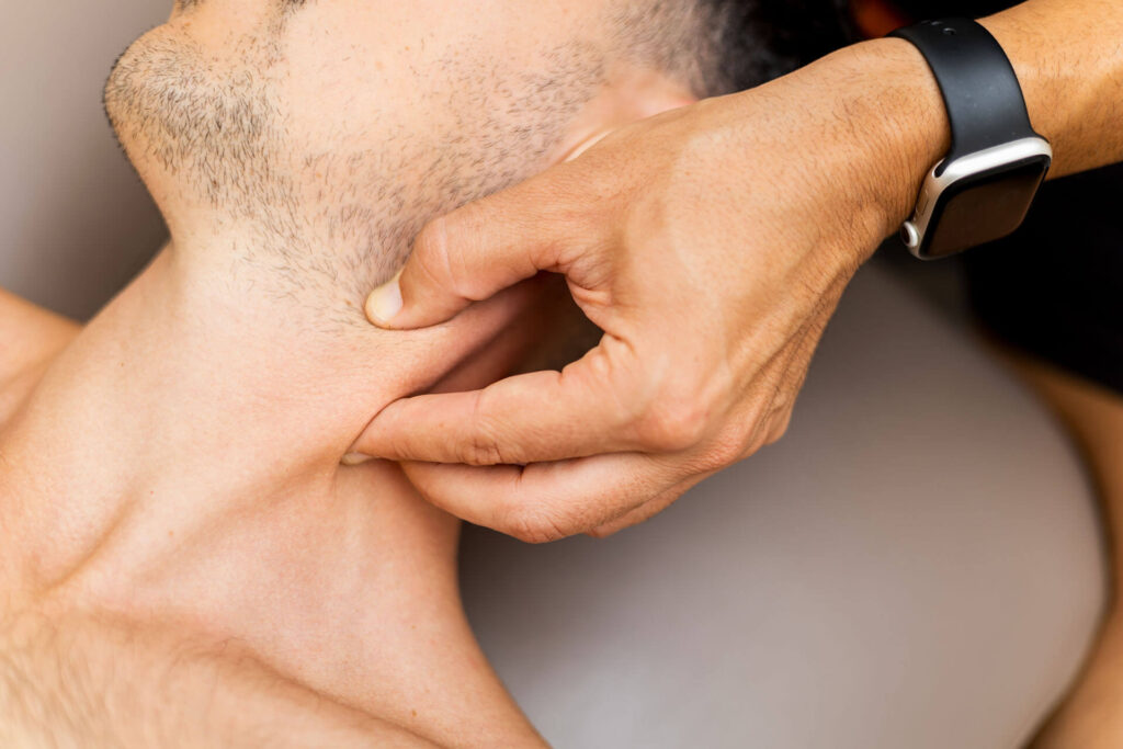 A person pinching the skin on their neck, indicating an area of pain, with a focus on pain management.